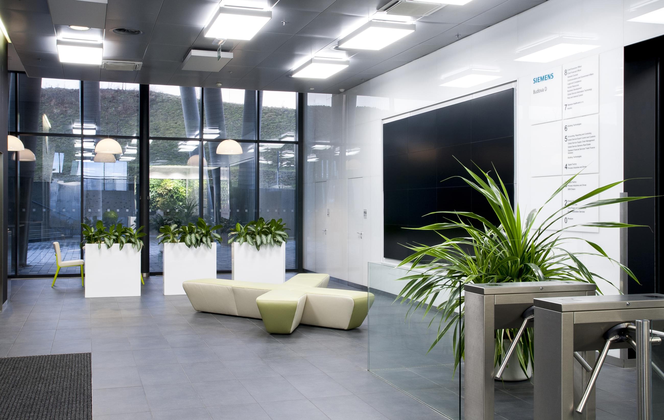 Atypické sofa vedle velkoplošných LCD umístěné ve vstupních prostorách společnosti Siemens.
