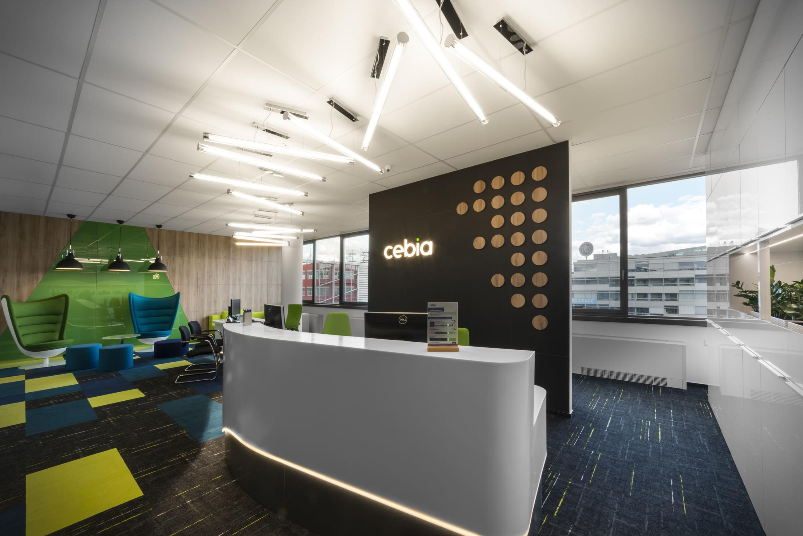 In the lobby there is a white reception desk and blue and armchairs by Actiu