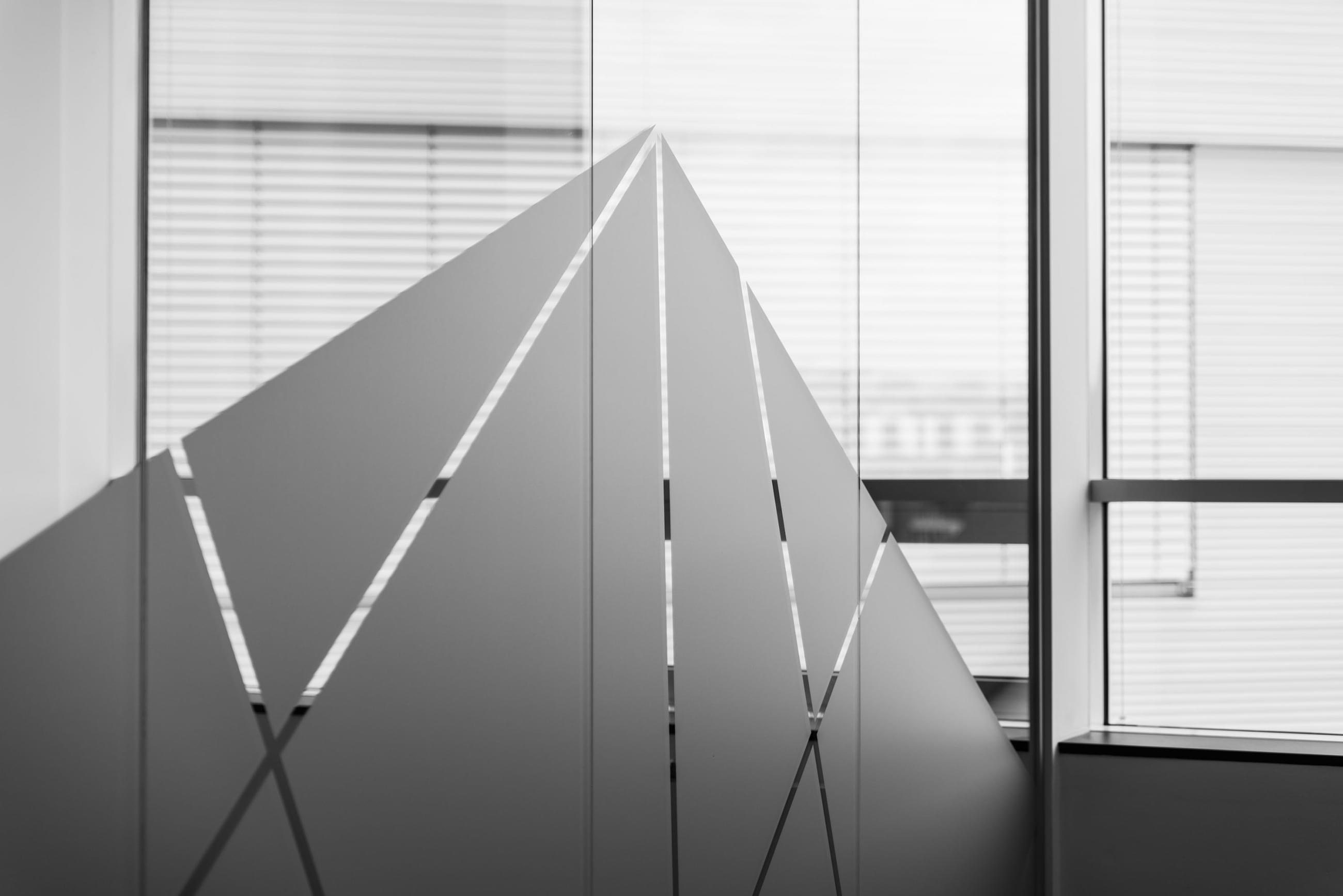 Polep na skleněné příčce s motivem šedých trojúhelníků a lichoběžníků zapadá do celkového konceptu prostorů.