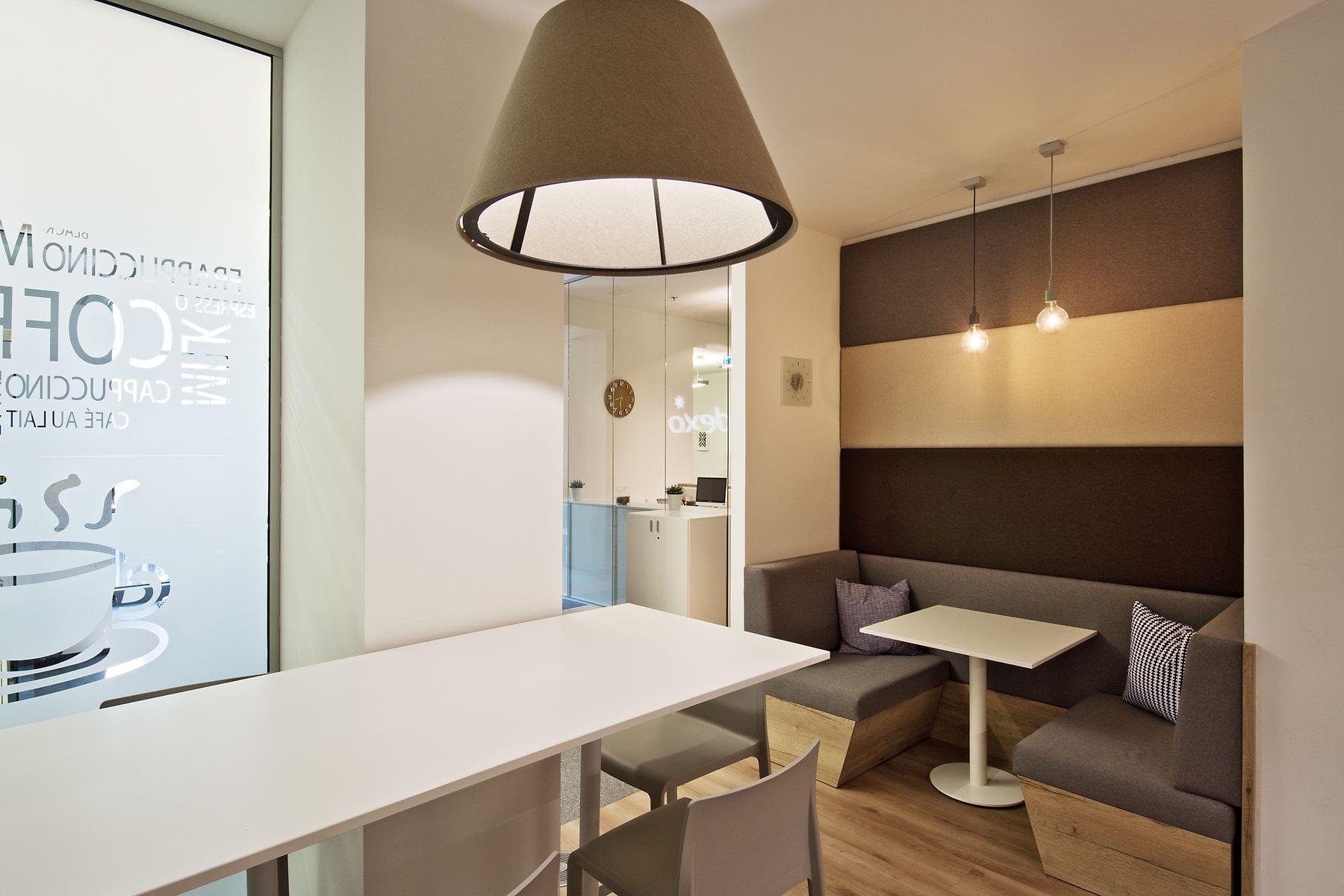 Posezení pro krátký meeting v tmavých tonech  se sladěnými akustickými panely na stěnách. 