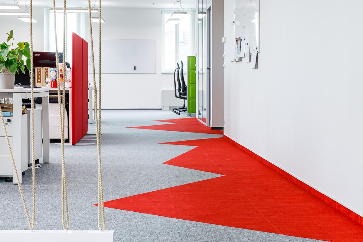 Designová kancelář s přírodními prvky a kobercem ve firemních barvách