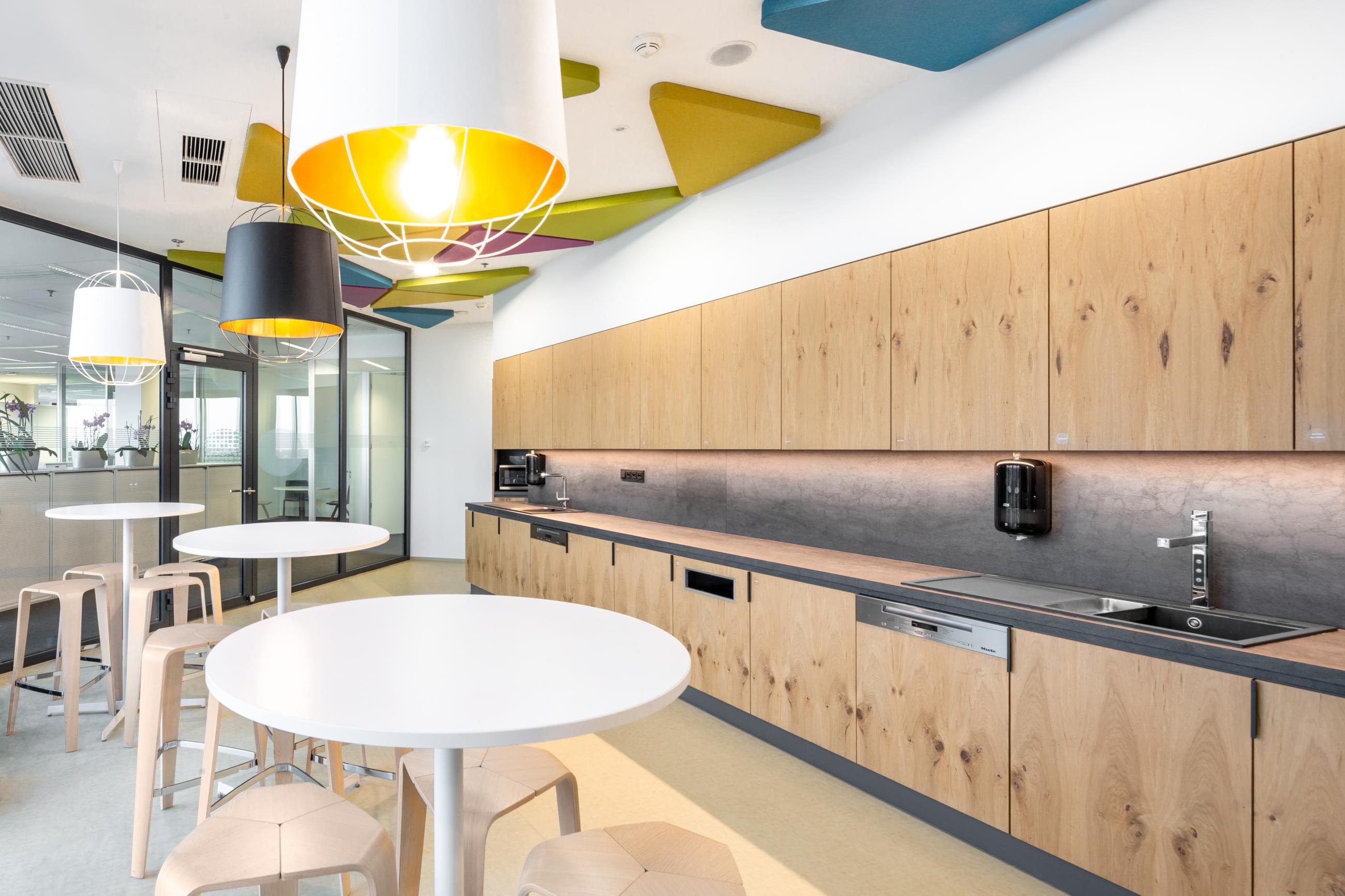 Kuchyňka pro zaměstnance s moderním interiérem a akustickými panely ve firmě Passerinvest. 