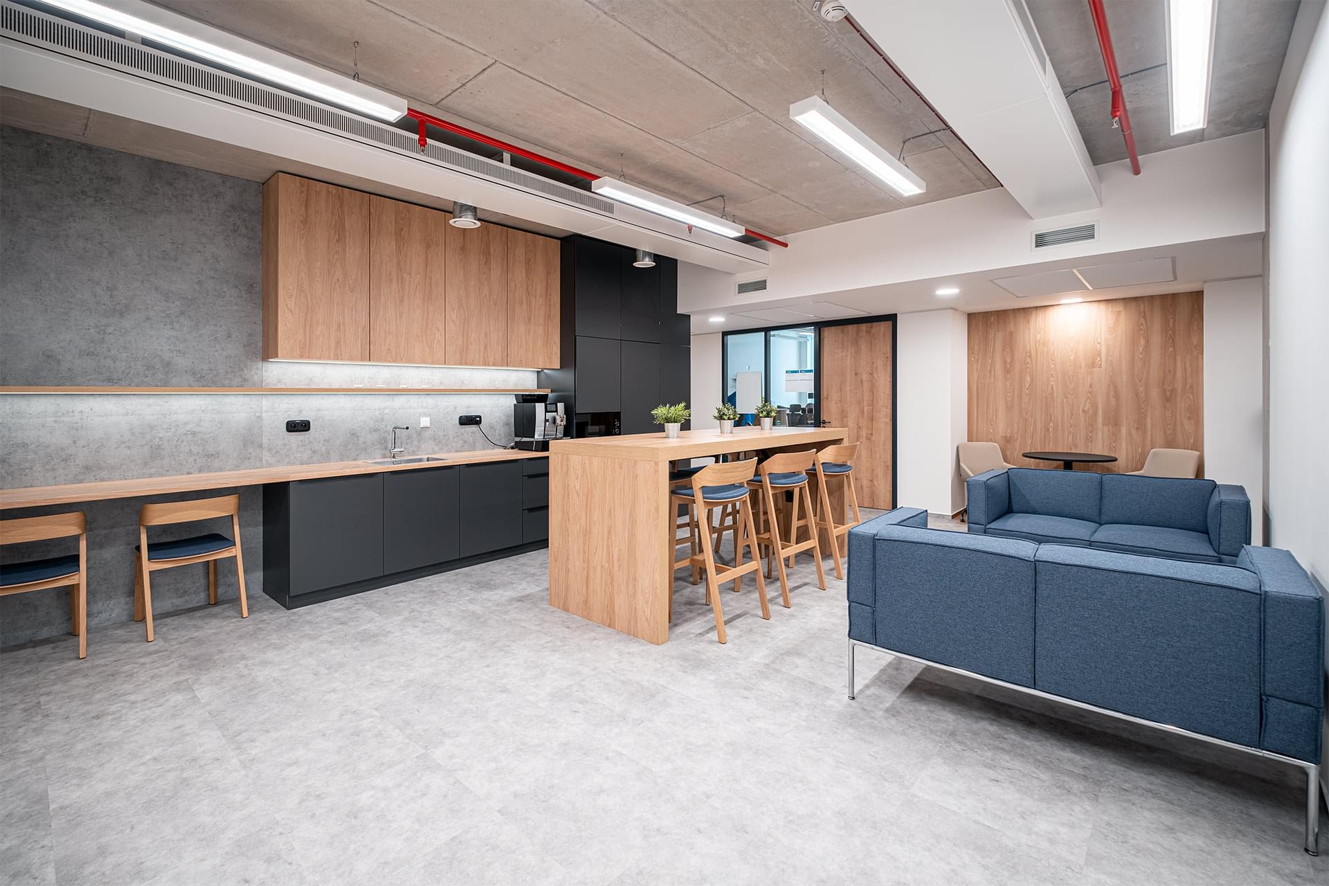 Moderní kuchyňka v dřevěném dekoru s barovým stolkem a židlemi v kancelářích OHLA ŽS