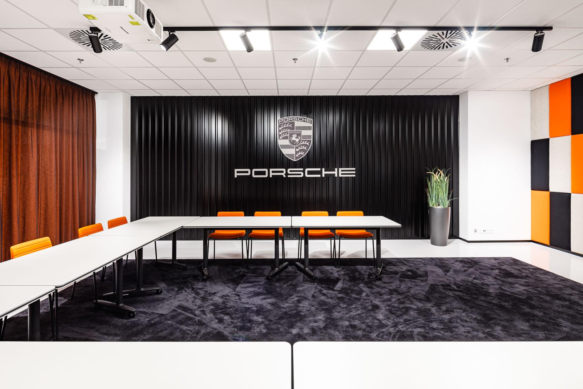 Zasedací místnost s velkým firemním nápisem Porsche