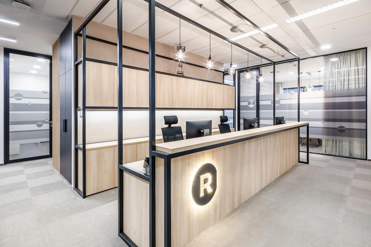 Recepce s přírodními prvky a kovovými příčkami s podsvíceným logem v kancelářích ROWAN LEGAL