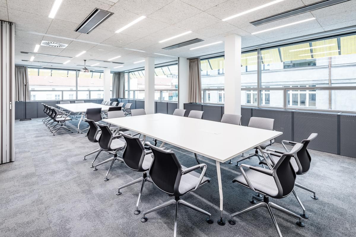 Zasedací místnost s posuvnou bílou stěnou složenou z pěti dílů. 