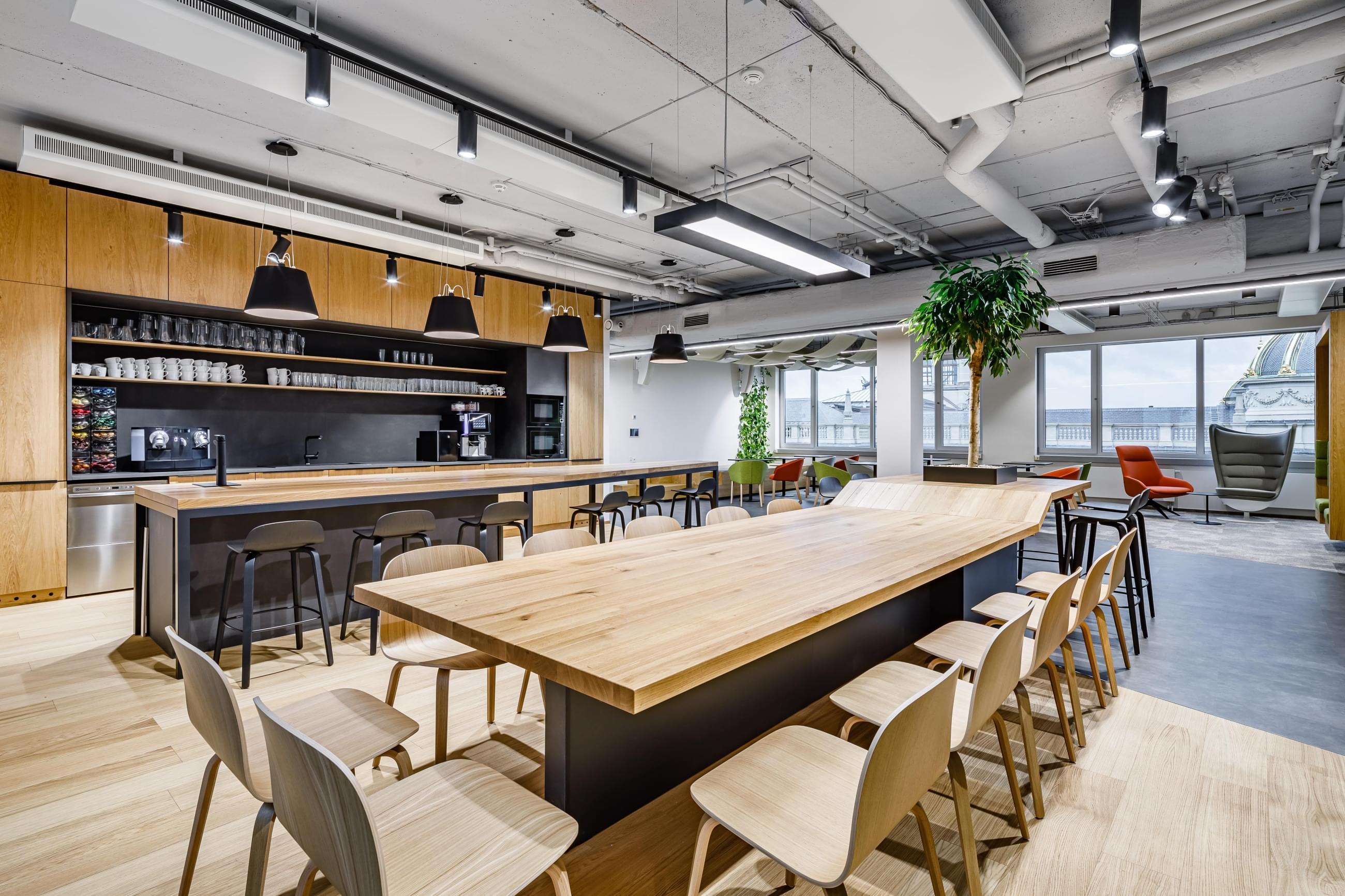 Minimalistická firemní kuchyňka s velkým barovým stolem a kuchyňským ostrůvkem 