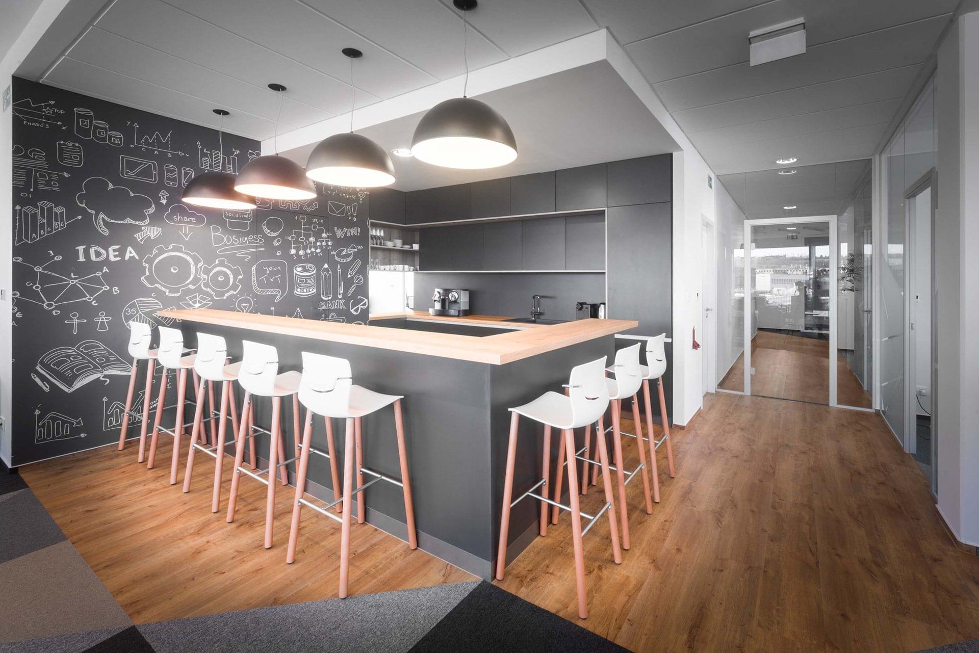 Kavárnu s obsluhou v tmavých tónech rozzáří světlo vycházející ze stropních svítidel ve spojení s dřevěnými a bílými prvky v podobě barového posezení a vinylu.