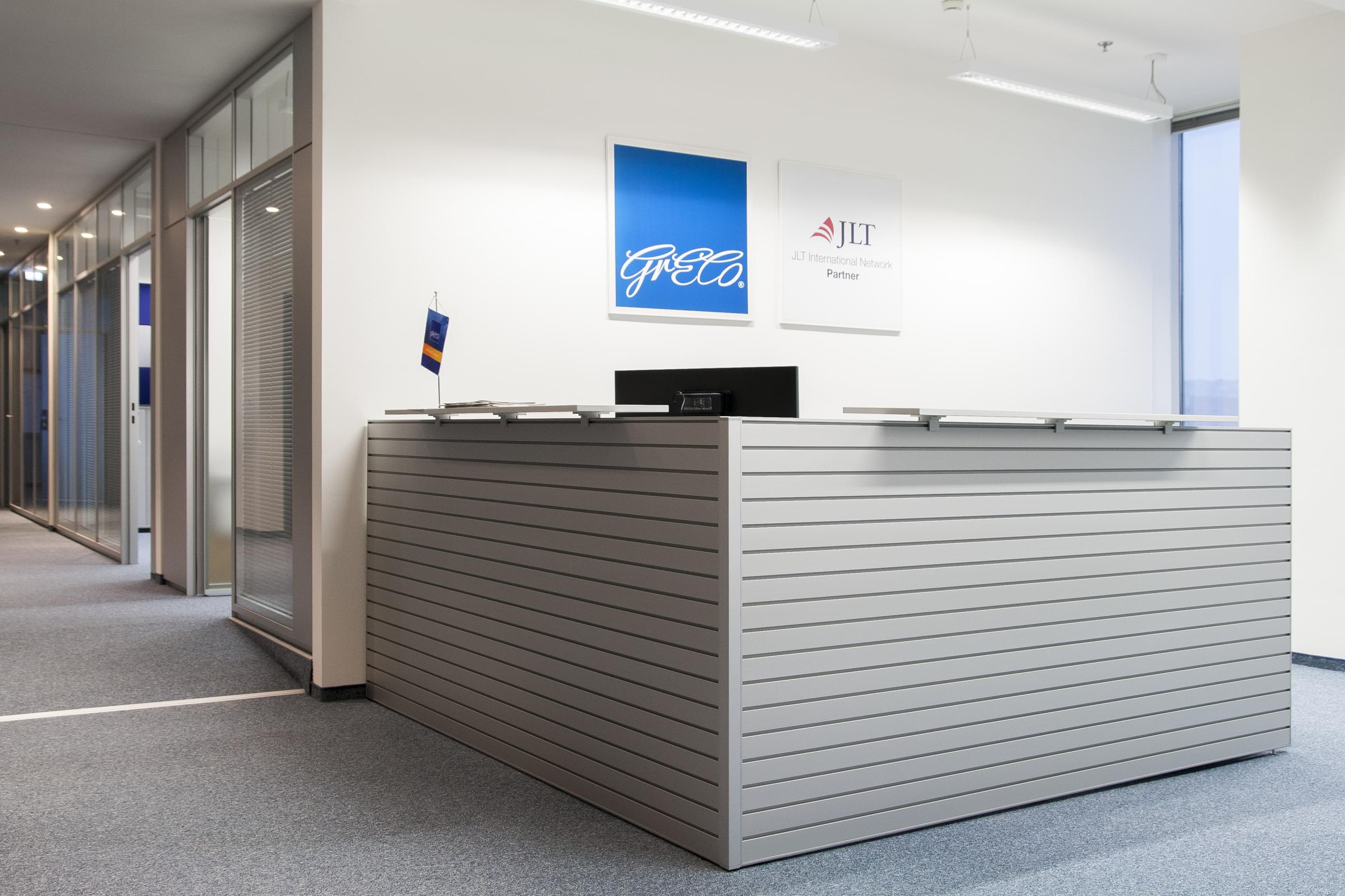 Recepce Greco v šedobílém provedení v Polus Tower je prakticky umístěna tak, aby nezabírala zbytečně mnoho prostoru a zapadala do designového konceptu.