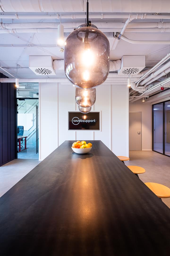 Corporate kitchen with long table and bar stools in industrial style in Websupport offices