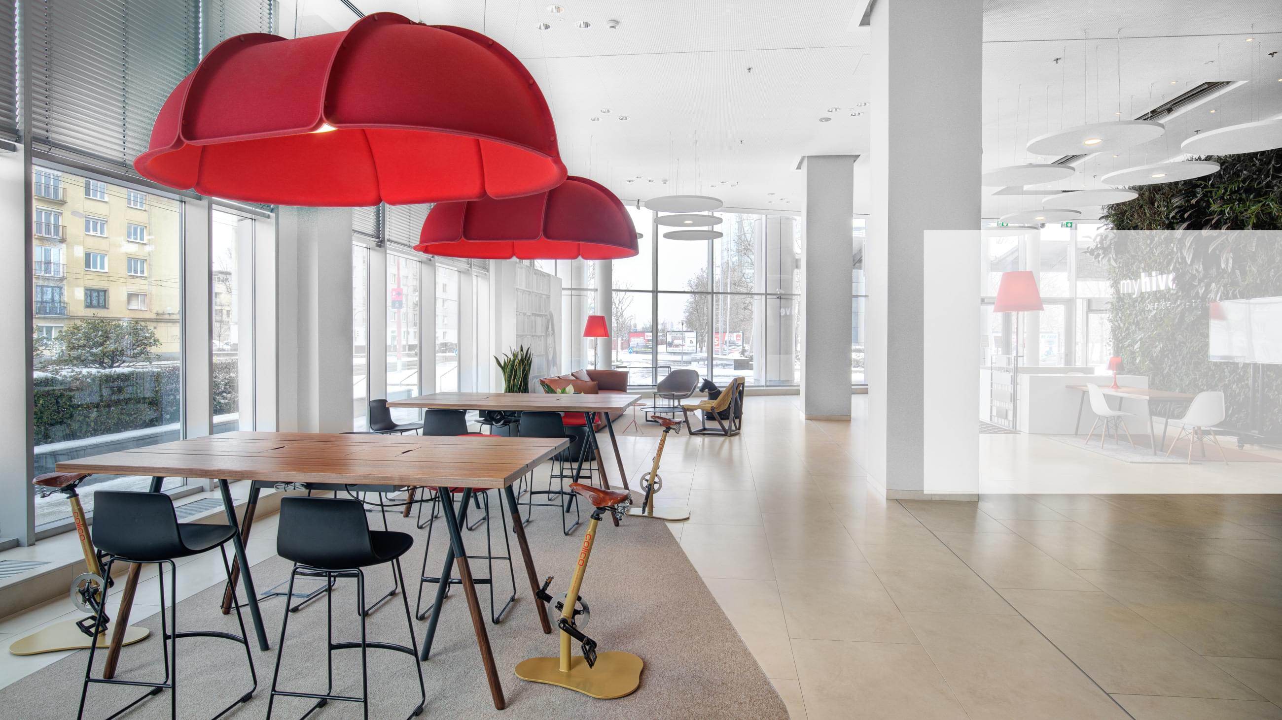 Pohled na relax zónu ve společnosti CAPEXUS. Pohodlné pohovky ve světlých barvách s tyrkysovými křesílky a bílými stolečky.