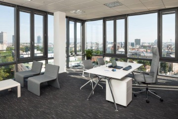 Budova CUBUS má kanceláře vybavené šedými designovými křesílky, bílými stolky a dalším kancelářským nábytkem.