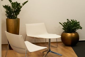 The white leather armchairs from Arper and the work armchair from Actiu create a fresh contrast to the dark rest of the reception