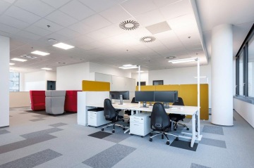 Pohled na mobilní pracovní místa ve složení kancelářských židlí, pracovních stolů na kolečkách a mobilních lamp.