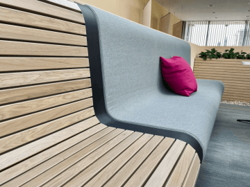 Wooden bench with seat cushions in magenta company colours