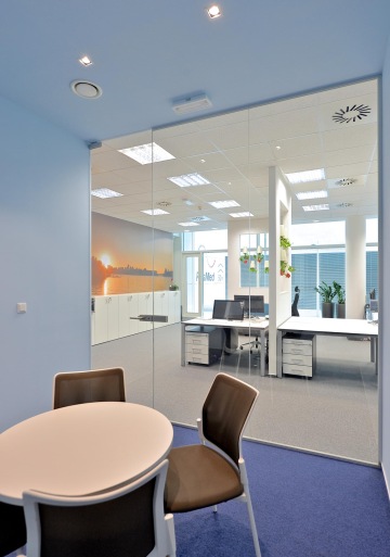 A view through a glass partition at office meeting room, into illluminated open space.