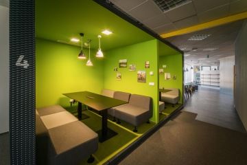 The green seating area with upholstered seating allows employees to work outside the workplace.