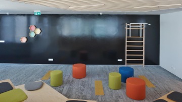 Relax zóna je vybavena žebřinami a šipkami, k posezení jsou zde zelené a oranžové taburety.