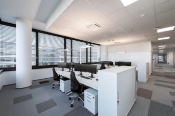 Pracovní místa v openspace kancelářích s přidruženými velkými úložnými prostory vedle pracovních stolů, kde jsou části openspace odděleny krátkými zdmi.