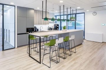 Jídelní místnost s protáhlým stolem a lavicí na sezení v kancelářích Samsung