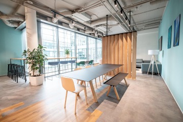 Jídelní místnost s protáhlým stolem a lavicí na sezení v kancelářích Samsung