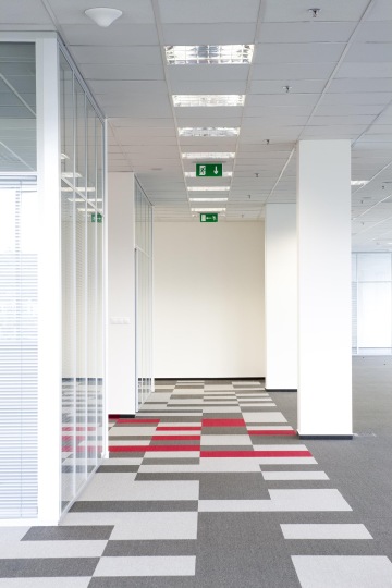 Detailed view of the carpet tile Voxflor that are in the color combination dark gray, light gray and red, and are playfully distributed across the floor.