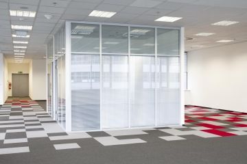 View of the glassed meeting room, which is set in the space and surrounded by a square motif carpet, which is revived by red squares.