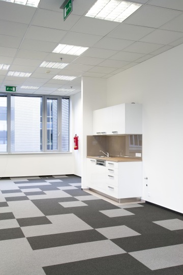 A view of the kitchen in bright shades set in the corner next to the wall with windows that provide natural light.