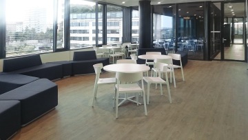 Odpočinková a jídelní zóna je vybavena kulatými stoly a židlemi v bílé barvě a dále modulovými pohovkami v tmavě šedé. Nábytek je od společnosti Actiu.