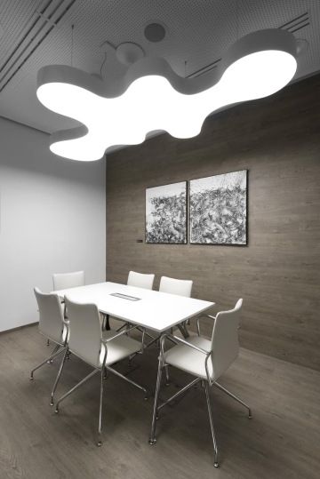 Zasedací místnost je zařízená bílým nábytkem Actiu. Dekor podlahy přechází plynule na stěnu, na které jsou pověšeny dva černo bílé obrazy.