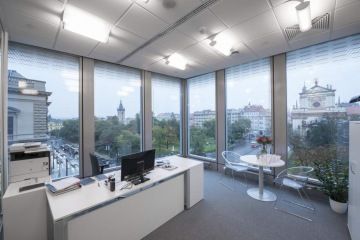 Illuminated office at Charles Square Center with white work desk and coffee table overlooking Charles Square.