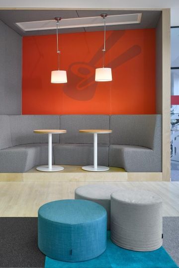 Zóna s čalouněnými lavicemi v šedé barvě slouží k odpočinku a díky dostatku zásuvek také k práci.