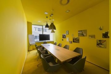 The meeting room with yellow walls, ceiling and painting as well is complemented by unusual lighting.
