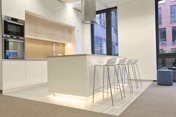 Kuchyňka a k ní přilehlé posezení v prostorách showroomu Candy a Hoover, které jsou převážně v bílém a světlém provedení s čistými liniemi.