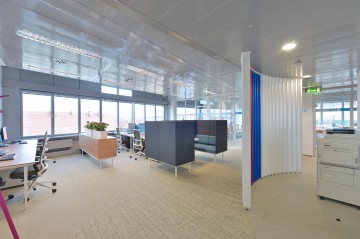 Open space of offices in the building Zlatý Anděl. White wall with blue space separators and gray sofa from ACTIU
