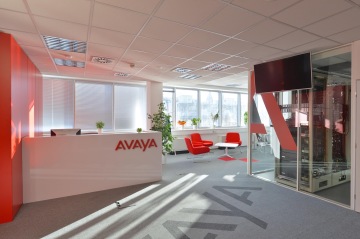 Recepce společnosti AVAYA v bílé barvě s červeným logem, šedý koberec, červená křesla a bílý stolek