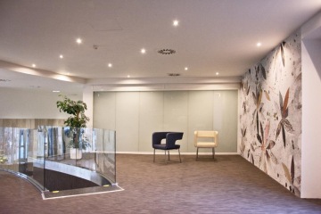 Flower design wallpapers for Artiga, small lights on the ceiling, white and black armchairs.