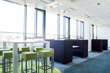 Prostor s moderním interiérem v odstínech zelené barvy doplňují barové židle a boxy pro setkávání kolegů.