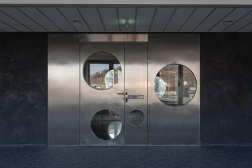 New modern metal entrance door of the ARBES Technologies company with glassed circular elements.