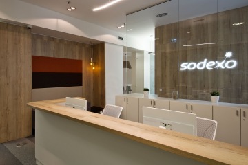 Reception with wooden cladding and glass partition enlightened with backlit logo.
