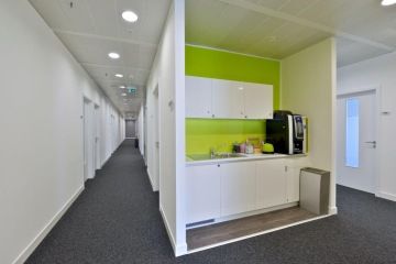 In the new Office for Regus office in New Butovice Park there are also coffee points for employees. The bright kitchen area is complemented by a green wall behind the line.