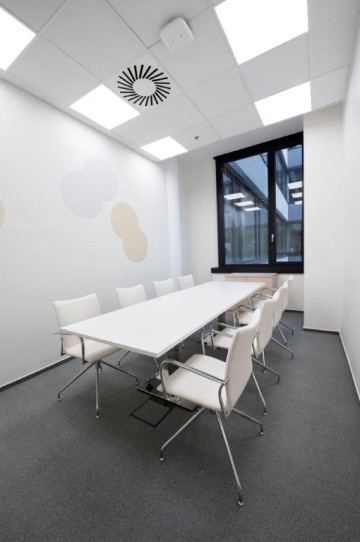Zasedací místnost pro osm lidí, kde je dominantou dlouhý bílý stůl doplněný o elegantní bílá křesílka na kolečkách.