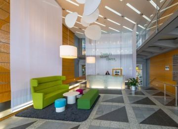 Revitalizace vstupní recepce v Charles Square Center, zelená sedací souprava pro zákazníky, bílá recepce s logem v pozadí.