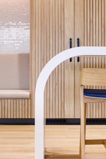 wooden built-in cupboards and wooden padded chairs at the rounded bar counter