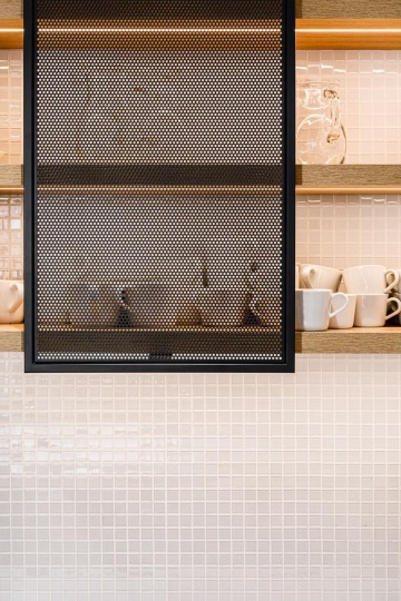 kitchen shelf with cups and black metal door
