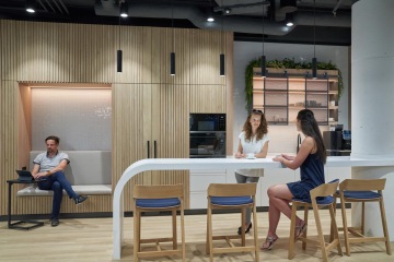 Velký barový stůl uprostřed firemní kuchyňce z přírodních materiálů