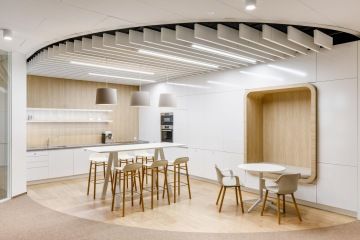 Pracovní kuchyňka ve světlých barvách vhodně doplněna o pohodlnou pohovku pro zaměstnance firmy ČAP