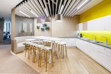 Světlá pracovní kuchyňka s barovým pultem a sezením pro obědové přestávky ve firmě ČAP.