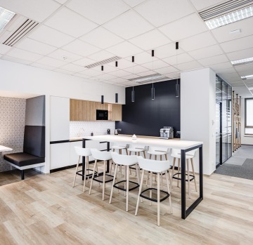 Firemní kuchyň v moderním provedení s barovým stolem a židlemi