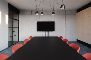 Meeting room with concrete wall, TV and red chairs